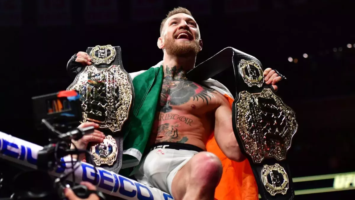 Conor McGregor dans la cage de l'UFC avec ses ceintures