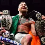 Conor McGregor dans la cage de l'UFC avec ses ceintures