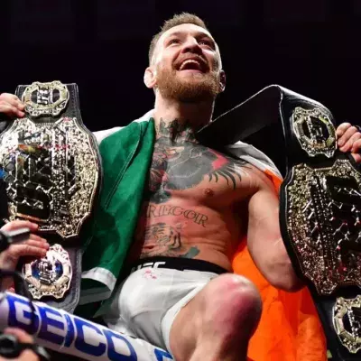 Conor McGregor dans la cage de l'UFC avec ses ceintures